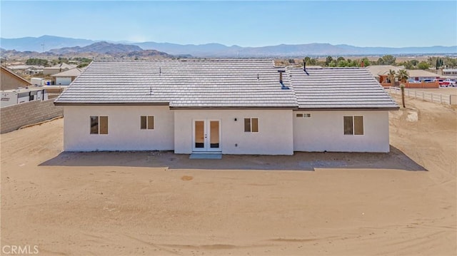 back of property with a mountain view and french doors