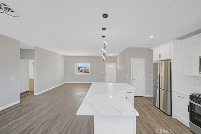 kitchen with light stone countertops, appliances with stainless steel finishes, light hardwood / wood-style flooring, a center island, and white cabinetry