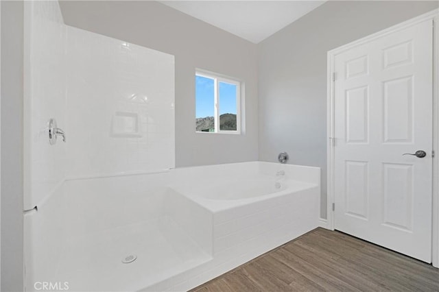 bathroom featuring hardwood / wood-style flooring and a relaxing tiled tub