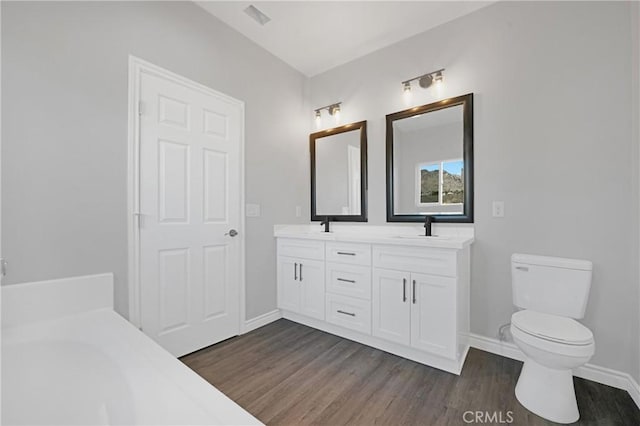 bathroom with toilet, vanity, and hardwood / wood-style flooring