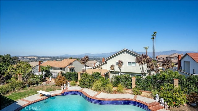 view of swimming pool with a mountain view and a diving board