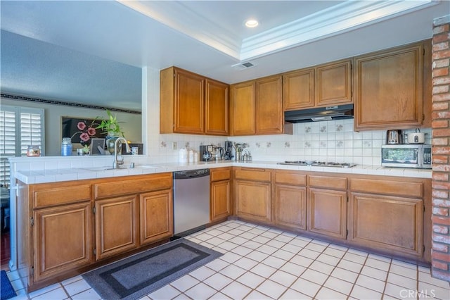 kitchen featuring sink, stainless steel appliances, backsplash, kitchen peninsula, and tile countertops