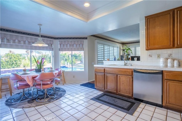 kitchen featuring dishwasher, sink, decorative light fixtures, decorative backsplash, and tile counters