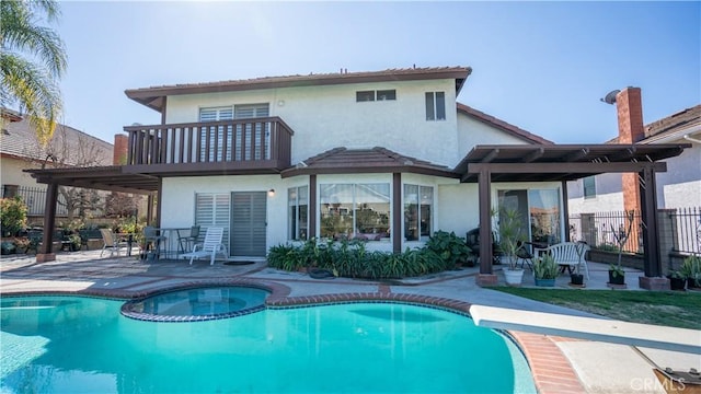 rear view of property with a pool with hot tub, a patio area, and a balcony