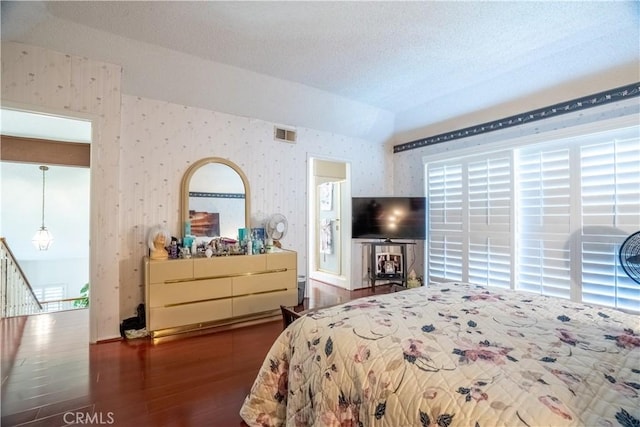 bedroom featuring a textured ceiling, lofted ceiling, and dark wood-type flooring