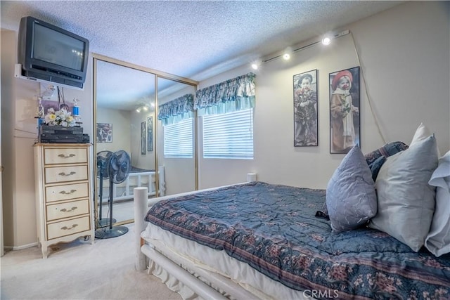 carpeted bedroom with rail lighting and a textured ceiling