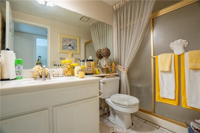 bathroom featuring tile patterned flooring, vanity, toilet, and a shower with door