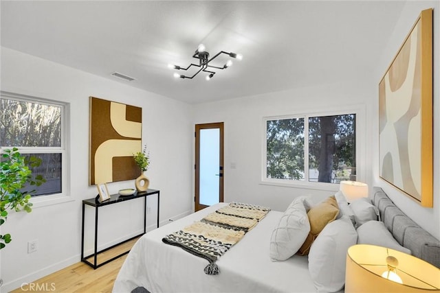 bedroom with a chandelier and light wood-type flooring