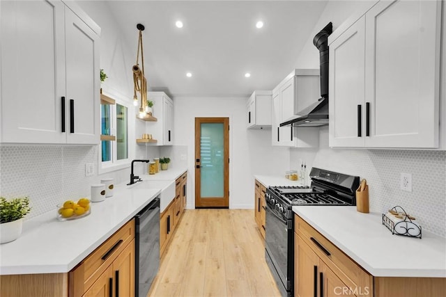 kitchen featuring sink, black appliances, light hardwood / wood-style flooring, white cabinetry, and hanging light fixtures