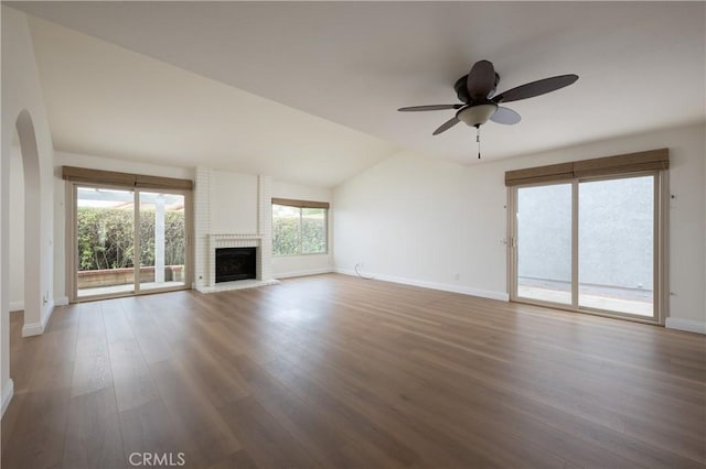 unfurnished living room featuring ceiling fan, wood-type flooring, lofted ceiling, and a brick fireplace