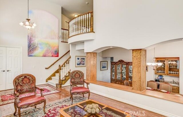 2034 Virazon Dr, La Habra Heights, CA 90631 - living room with arched walkways, a chandelier, wood finished floors, a towering ceiling, and stairway