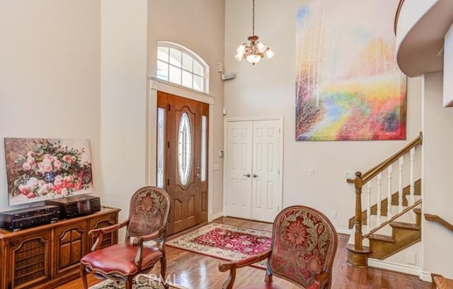 entryway with an inviting chandelier, a towering ceiling, and hardwood / wood-style flooring