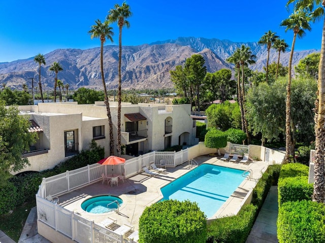 view of pool featuring a hot tub, a mountain view, and a patio