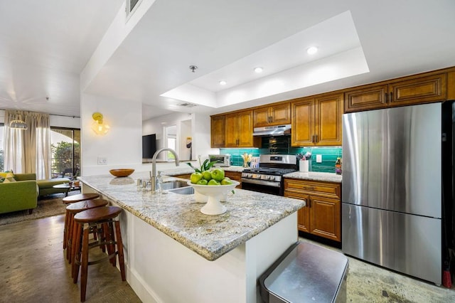 kitchen with a breakfast bar area, stainless steel appliances, a raised ceiling, and sink