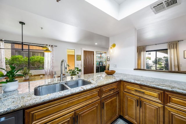 kitchen with light stone countertops, sink, and hanging light fixtures