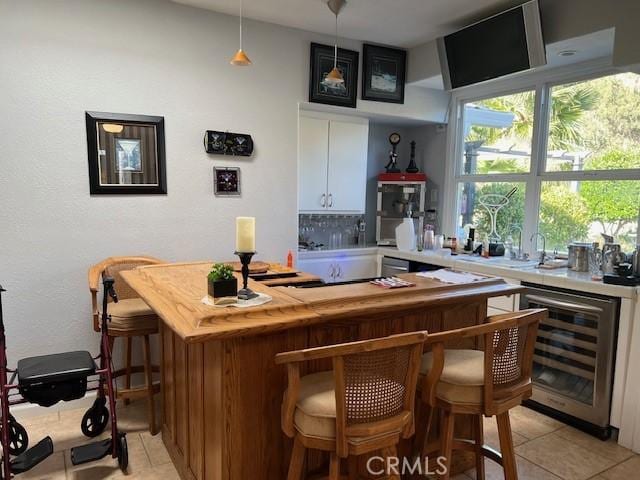 bar featuring white cabinets, decorative light fixtures, light tile patterned flooring, and wine cooler