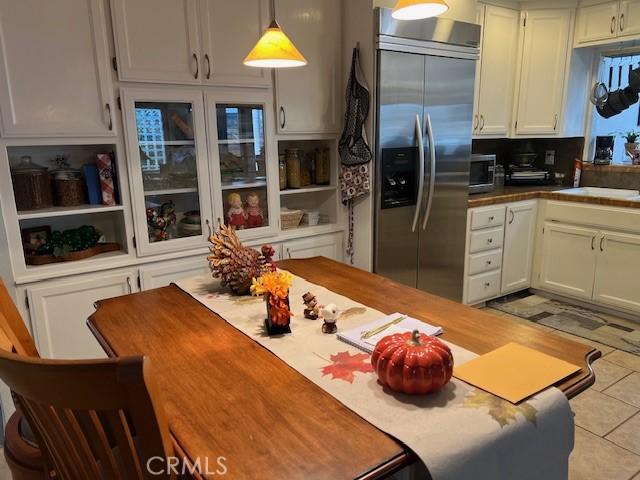 kitchen with decorative backsplash, stainless steel appliances, pendant lighting, light tile patterned floors, and white cabinets