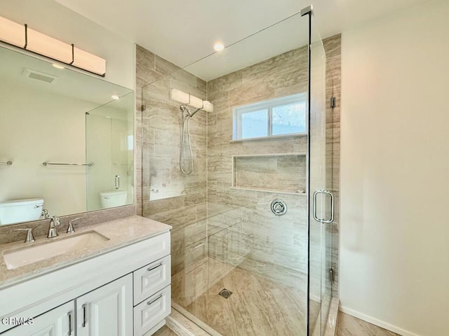 bathroom featuring vanity, toilet, and a shower with door