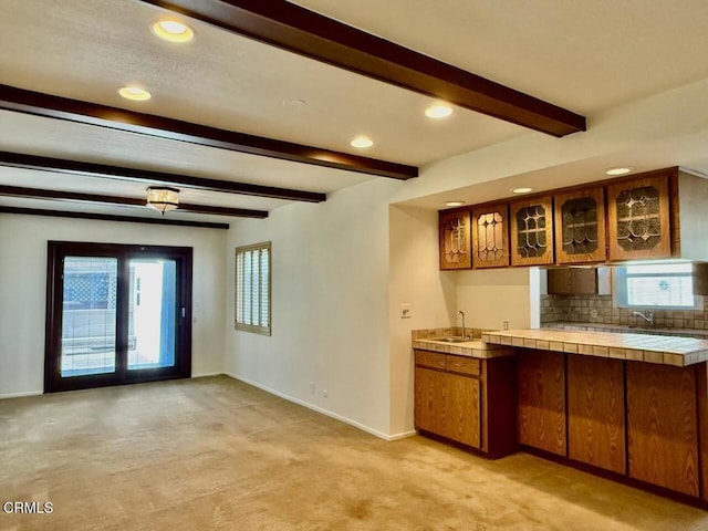 bar featuring tile counters, a healthy amount of sunlight, light colored carpet, and sink