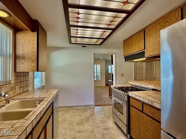 kitchen featuring appliances with stainless steel finishes, a wealth of natural light, tile counters, and sink