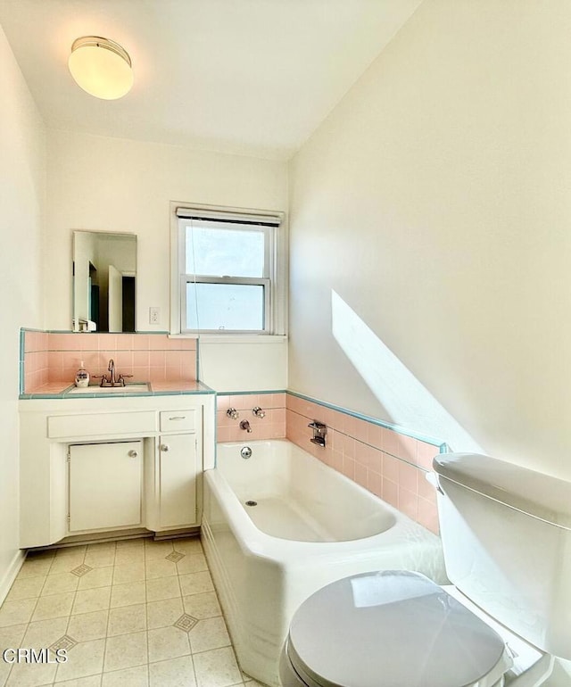 bathroom featuring toilet, a bath, vanity, and tile patterned floors