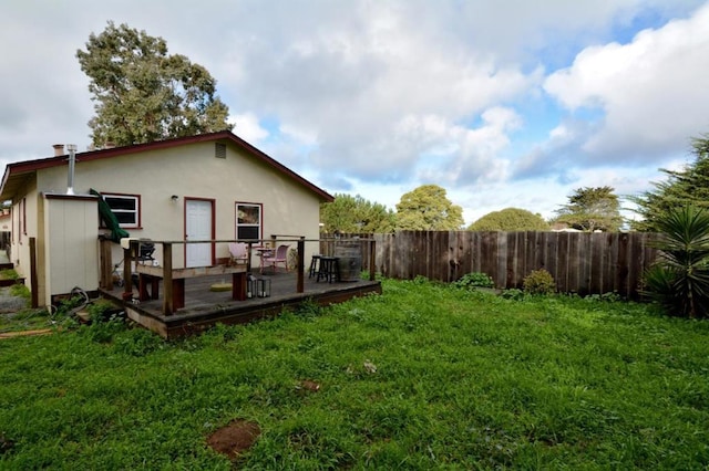 back of property with a wooden deck and a yard