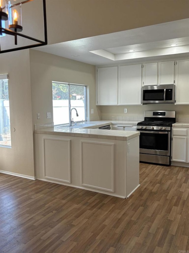 kitchen featuring tile countertops, white cabinetry, dark wood-type flooring, and appliances with stainless steel finishes