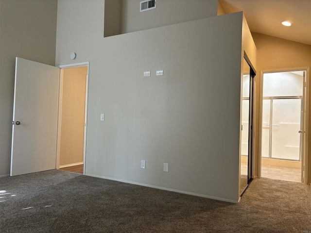 carpeted empty room with high vaulted ceiling