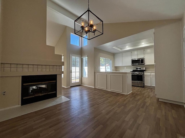 kitchen with appliances with stainless steel finishes, dark hardwood / wood-style flooring, pendant lighting, an inviting chandelier, and white cabinets