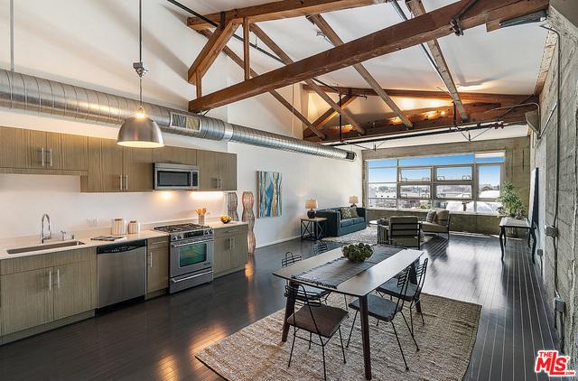 kitchen featuring dark hardwood / wood-style flooring, stainless steel appliances, sink, high vaulted ceiling, and hanging light fixtures