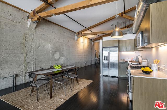 kitchen featuring beam ceiling, dark wood-type flooring, high vaulted ceiling, pendant lighting, and appliances with stainless steel finishes