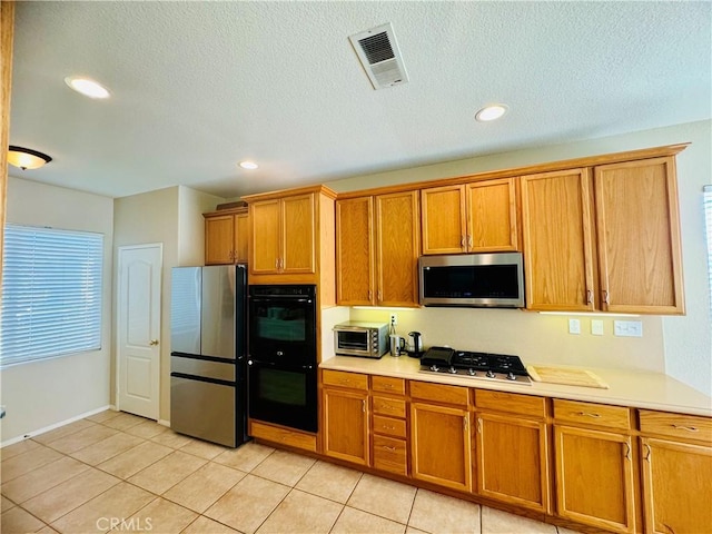 kitchen with light tile patterned floors, stainless steel appliances, and a textured ceiling