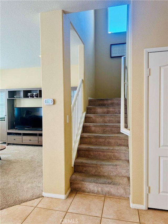 stairs featuring a wealth of natural light, tile patterned flooring, and a textured ceiling