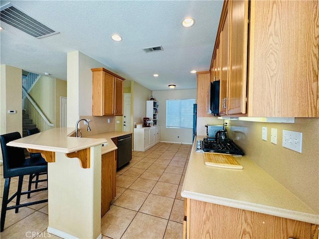 kitchen featuring a kitchen breakfast bar, sink, light tile patterned floors, black dishwasher, and kitchen peninsula