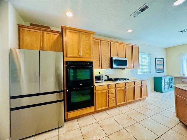 kitchen featuring light tile patterned floors, a textured ceiling, and appliances with stainless steel finishes