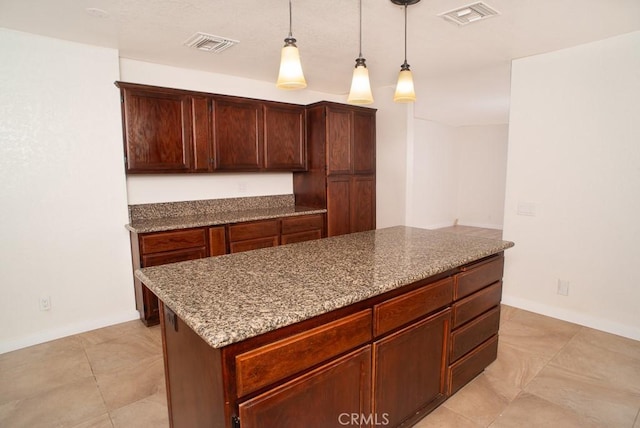 kitchen with light stone countertops, pendant lighting, a center island, and light tile patterned floors