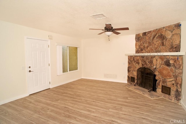 unfurnished living room with ceiling fan, a fireplace, wood-type flooring, and a textured ceiling