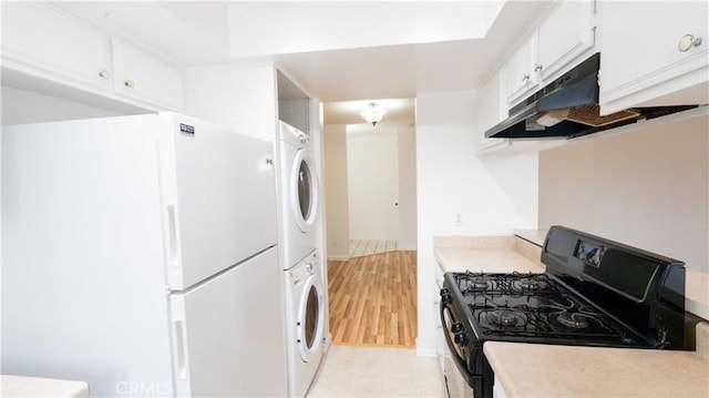 kitchen featuring light hardwood / wood-style floors, black gas range oven, white fridge, stacked washer and dryer, and white cabinetry