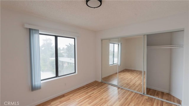 unfurnished bedroom with a textured ceiling, hardwood / wood-style flooring, and a closet