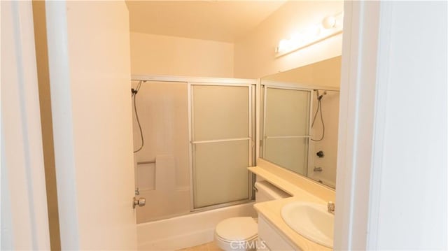 full bathroom with sink, bath / shower combo with glass door, and toilet