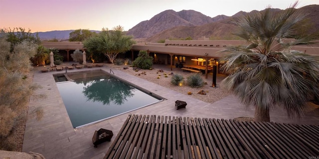 pool at dusk with a mountain view and a patio