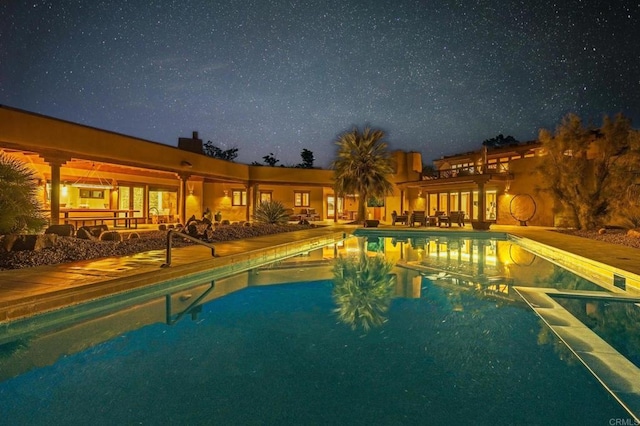 pool at twilight featuring a patio