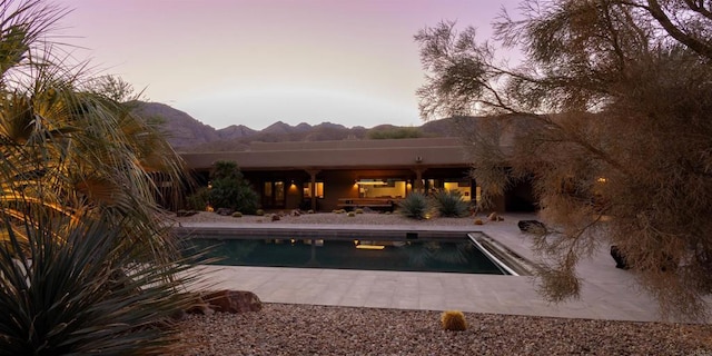 pool at dusk with a mountain view and a patio area