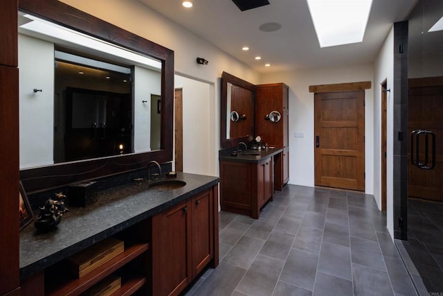 bathroom with vanity, a skylight, tile patterned floors, and a shower with door