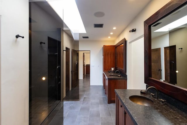 bathroom featuring vanity, a skylight, a shower with door, and tile patterned flooring