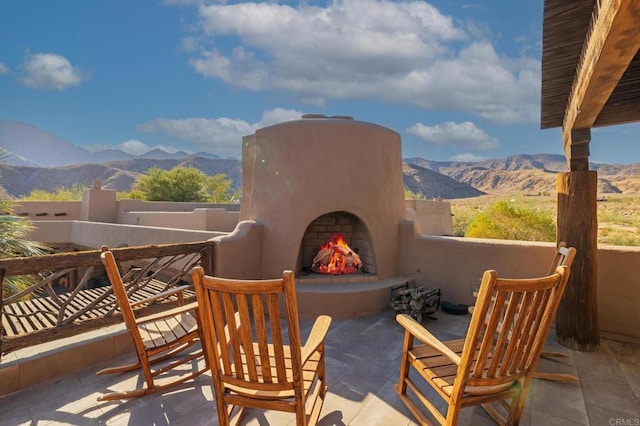 view of patio / terrace featuring exterior fireplace and a mountain view