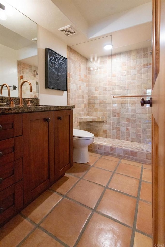 bathroom with tile patterned floors, vanity, a shower, tile walls, and toilet