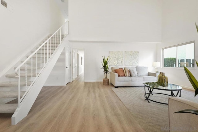 living room with a towering ceiling and light wood-type flooring