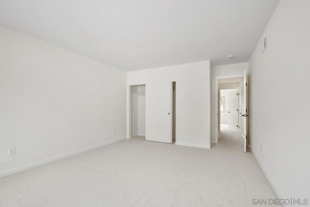 unfurnished bedroom with light carpet and a closet