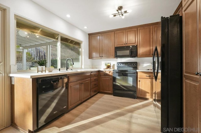 kitchen with sink, light hardwood / wood-style flooring, and black appliances